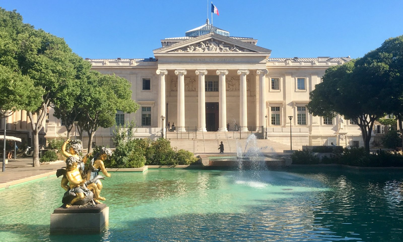 Le palais de justice de Marseille, son bassin et sa fontaine, sous un ciel bleu