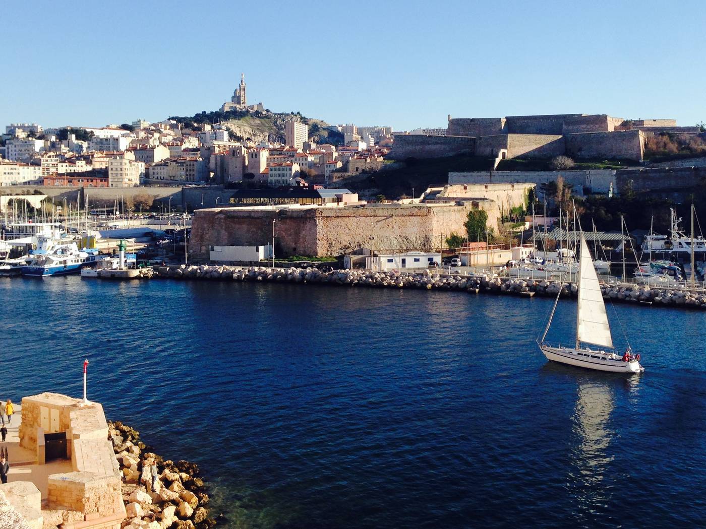 Le Vieux-Port de Marseille, un voilier et Notre-Dame de la Garde au-dessus des immeubles